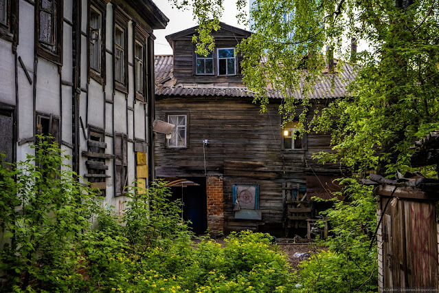 Старый деревянный дом с аркой за кустарником