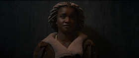 Close-up of a young Black woman playing the Angel, but wearing 21st century 'normal' clothing