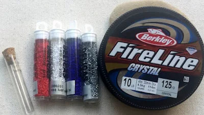 beading needles, tubes of delica beads in red, white, blue and silver and spool of FireLine beading thread