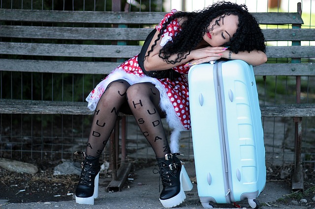 Girl Sleeping on a Park Bench, Head Resting on Her Suitcase