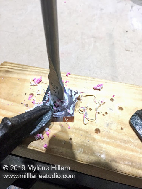 Using a spade bit to drill a hole in the resin slice to turn it into a ring