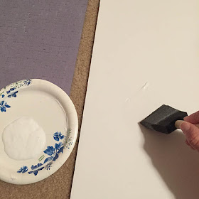 Foam brush applying glue to a white foam core board