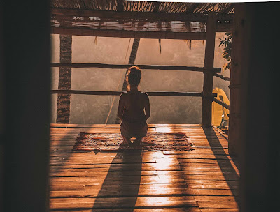 image of woman meditating on floor with overlooking trees