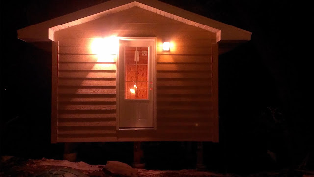 Outdoor sauna entry lights lit up at night.