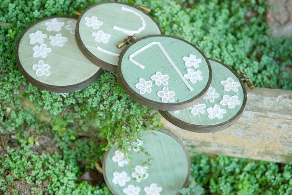 Painted tin cans to hold the flowers Yes please Embroidered table numbers