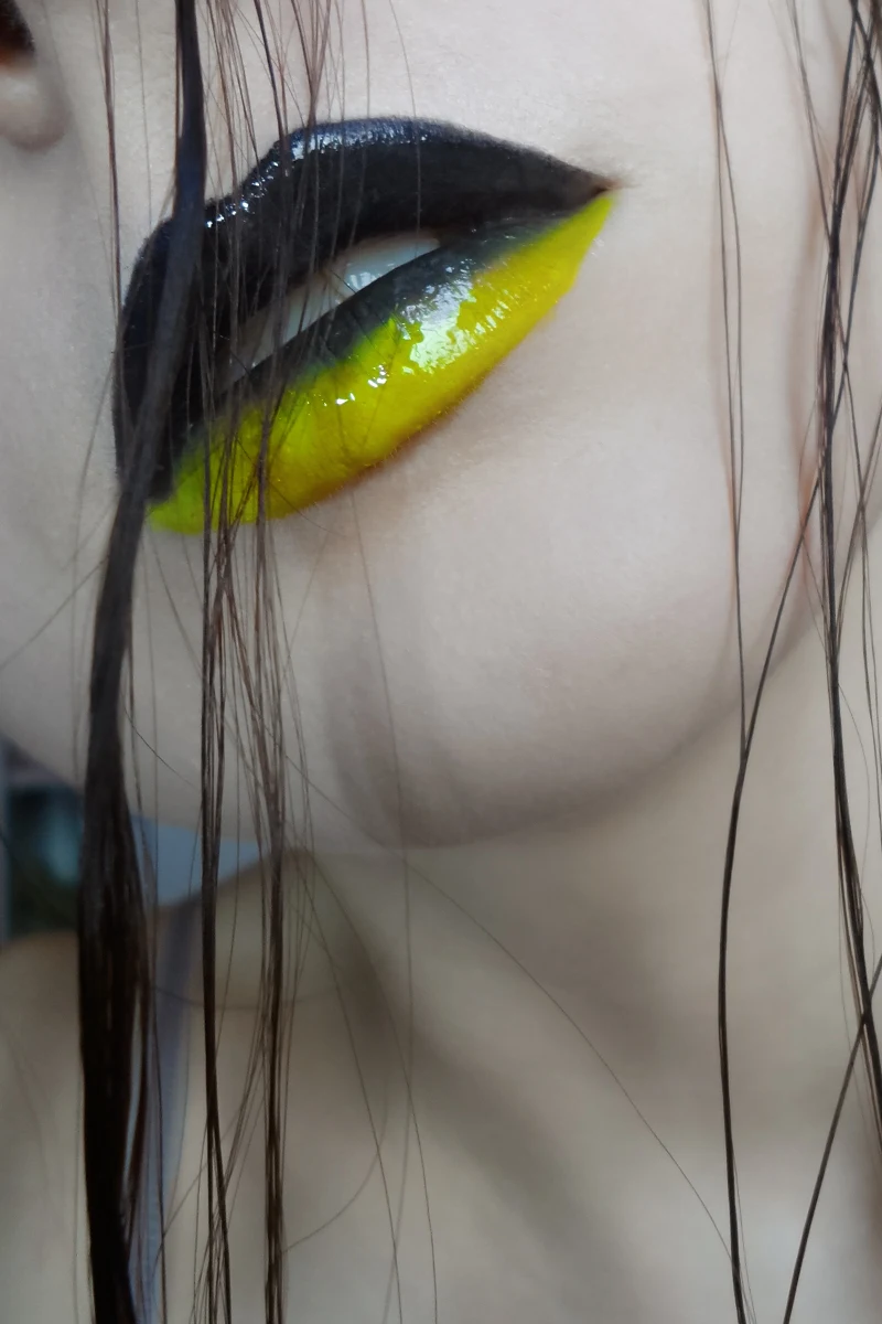 close-up of woman lips with editorial black and bright yellow lip look