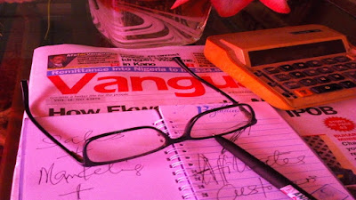 Affiliates business work table with eye glasses, notepad and pen newspaper, calculator and flowers.