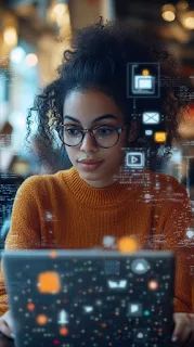 A young African American woman focuses intently on her laptop in a bustling coffee shop.