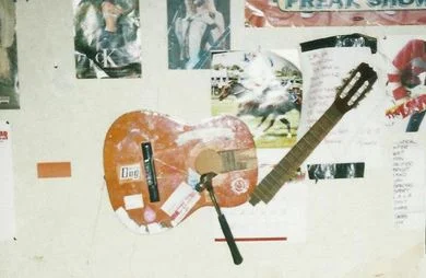 smashed up guitar on wall