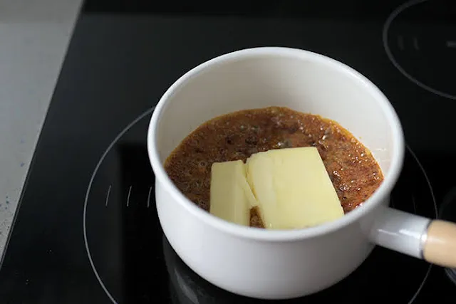 Add butter to caramelised sugar to make fruit cake