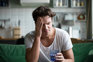 A man sitting on a sofa wincing in pain