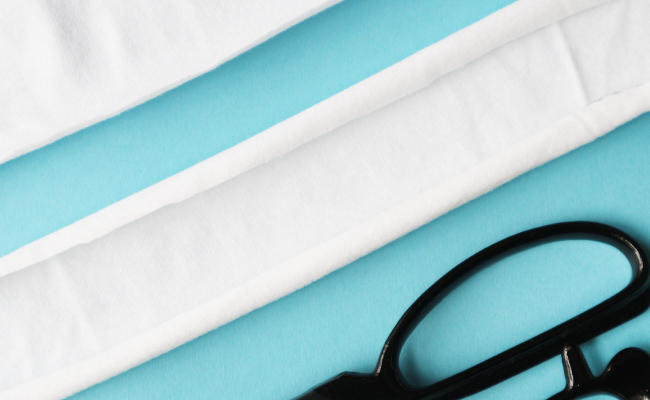 White jersey fabric cut into a strip to demonstrate the fabric rolling inwards.
