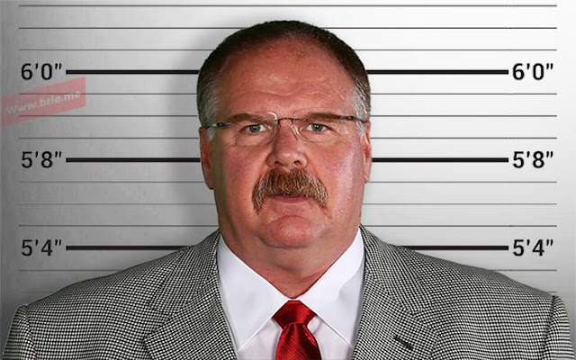 Andy Reid posing in front of a height chart background
