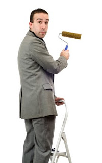 Businessman on a ladder with paint roller