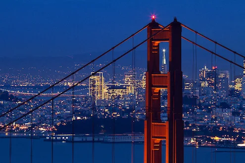 Espectacular detalle de noche de la Pirámide de Transamerica enmarcada en la estructura del Golden Gate Bridge de San Francisco