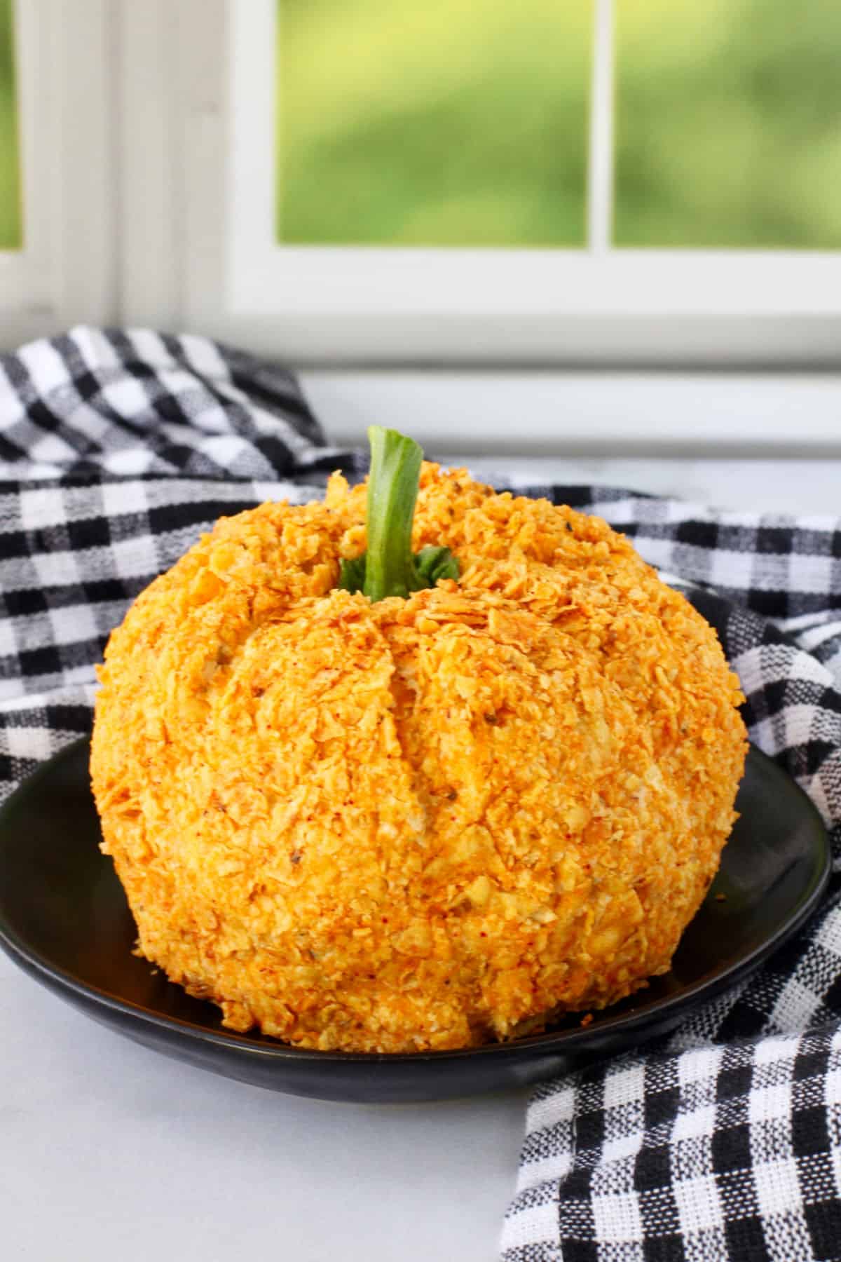 Pumpkin-Shaped Halloween Cheese Ball with a bell pepper stem on a plate.