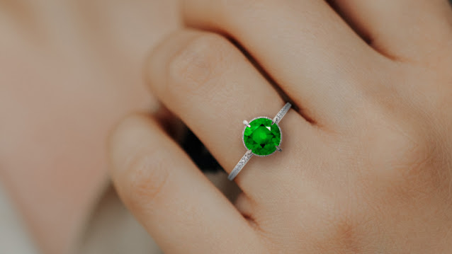 an emerald ring on a woman’s finger