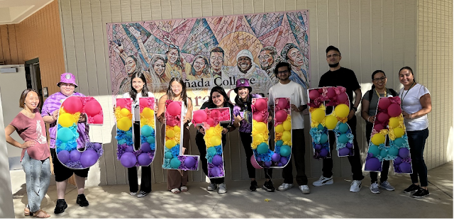 A group of students holding letters that form the word "Cultura" outside the new Cultural Center