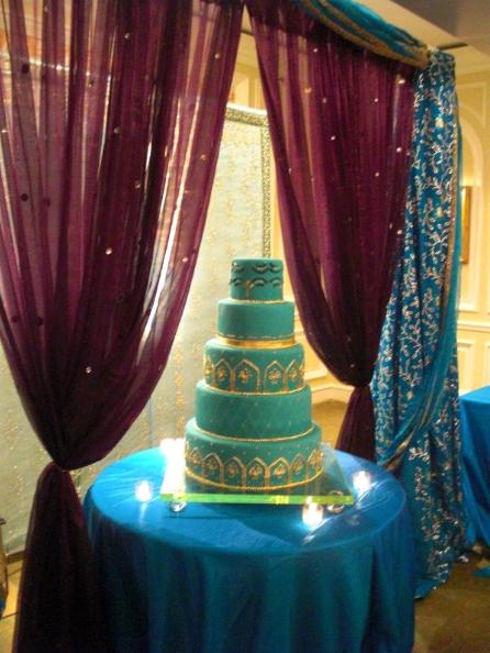 Squareshaped wedding cake and decorated with red feathers 