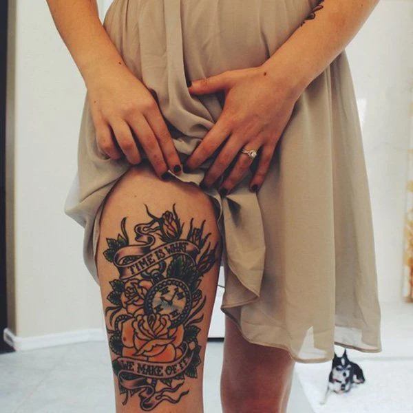 chica se levnta el vestido para enseñar un tatuaje en su perna de relog de bolsillo con rosas