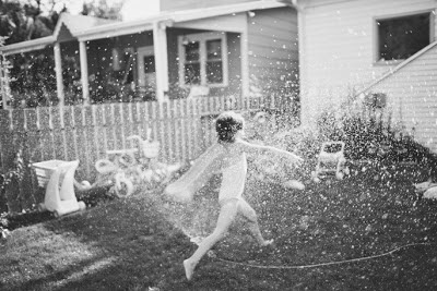 Foto de niña jugando en el patio con la manguera
