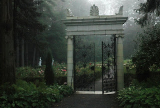 A white marble entry way into the gardens with mist all around.