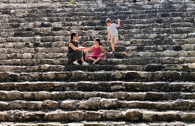 Mujer y dos niños en las escaleras de una pirámide en Cobá