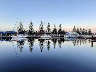 yacht reflections in water with pine trees