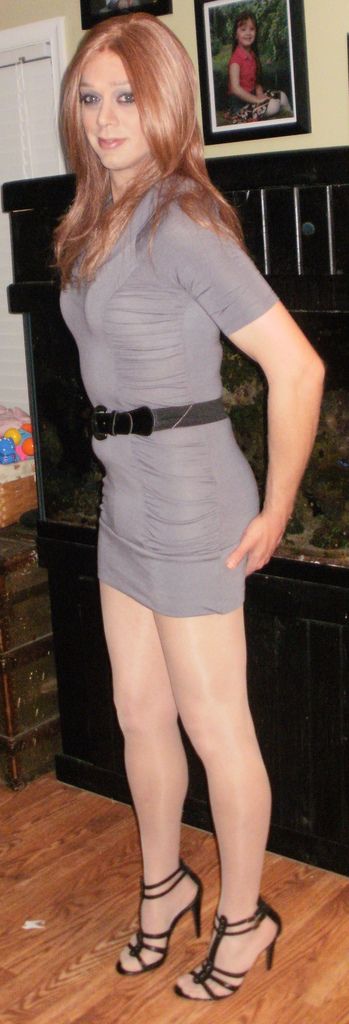 Stunning crossdresser in a gray short dress combined with shiny pantyhose and high heels