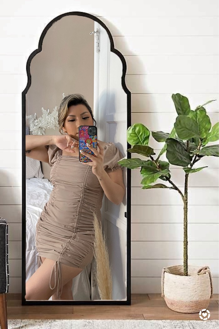 Girl taking a selfie mirror wearing a nude ruched dress.