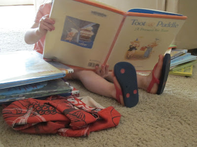 elder lass reading a library books with other library books stacked nearby