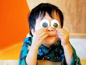 boy holding up very large googly eyes