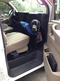 Coach is standing in the wheel well of the van looking out the open door.