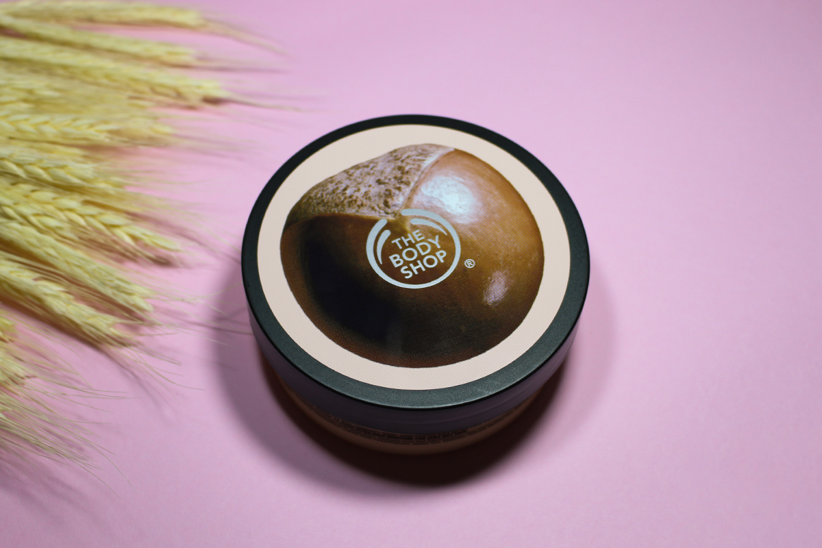 close-up of an opened pot with the Nourishing Body Butter by The Body Shop on a pink background