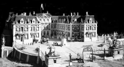 b/w image of Versailles Palace forecourt with grills, gate and guard blocks.