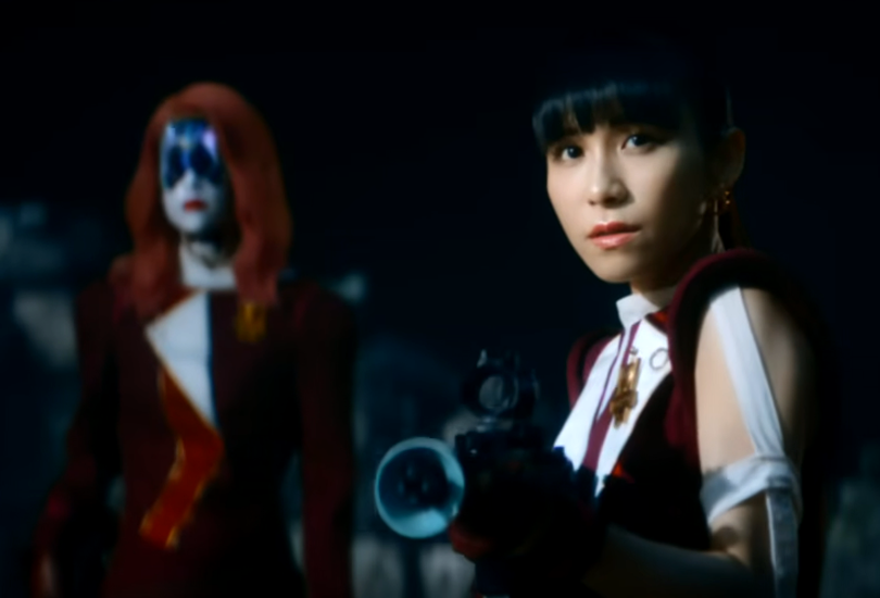 Perfume drop a teaser for Nebula Romance: Part 2, which sees them confronting Emperor Palpataka | Random J Pop A screenshot from Perfume’s teaser video for Nebula Romance: Part 2, featuring a-chan with a gun as Kikimo is stood behind her.