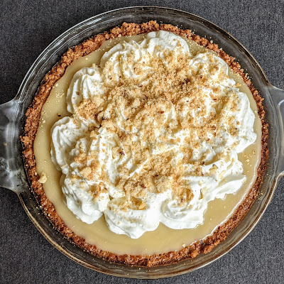 Overhead shot of a caramel custard pie, toppied with whipped cream and cookie crumbles