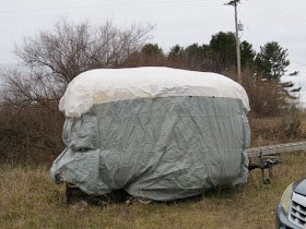 small travel trailer covered for the winter