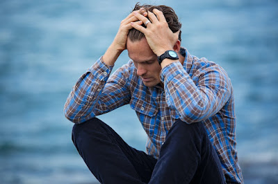 A visually distressed man holding his head