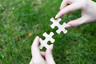 Close-up of hands putting together two puzzle pieces