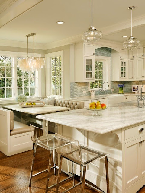 beautiful traditional kitchen with built in banquette dining table seating and ghost acrylic bar stools marble island modern lighting