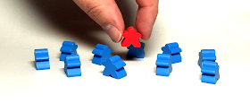 A red meeple is being picked up from a crowd of blue meeples.