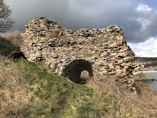 A close up shot of the ruins of the lime kilns showing that it is a crumbling stone structure with grass all around and bushes growing up to the left of it.  Photograph by Kevin Nosferatu for the Skulferatu Project.