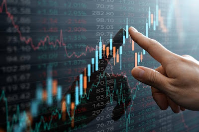 "A hand pointing at a digital stock market chart showing fluctuating candlestick graphs and financial data."