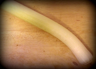 A leek on a wooden chopping board