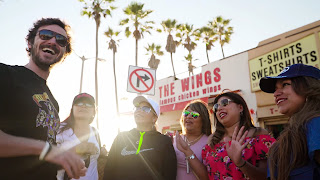 A man and 5 women outside a row of beach shops