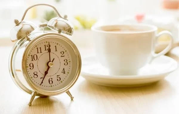 An alarm clock and a cup of tea.