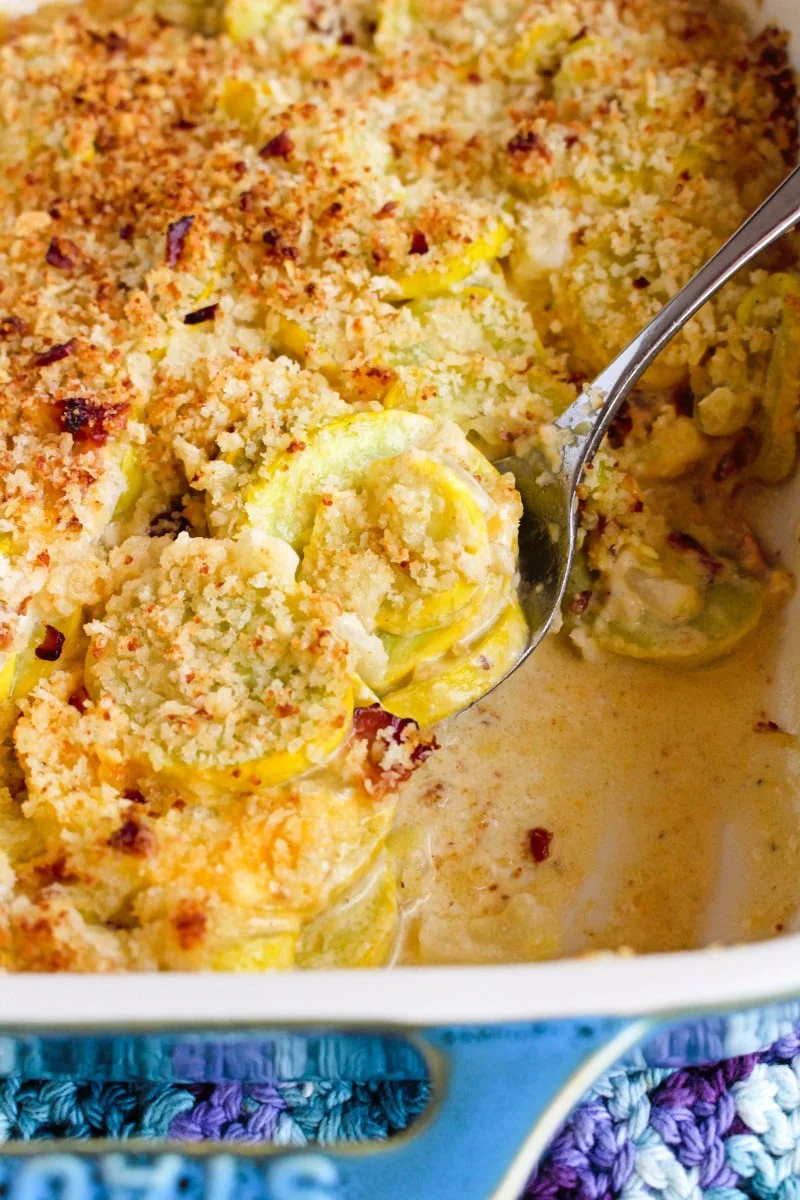 Side view of Yellow Squash Casserole with Bacon in a teal casserole dish.