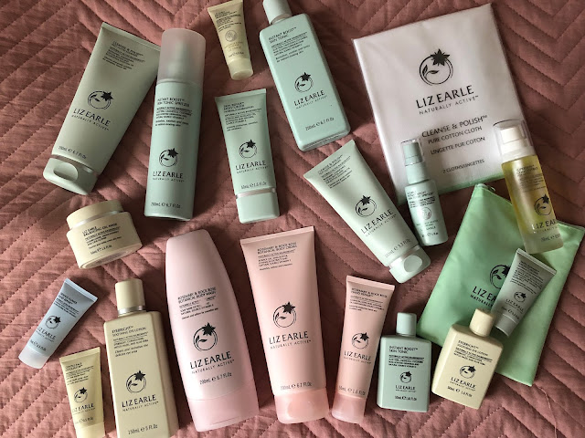 Large variety of Liz Earle products on pink quilt