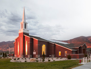 The sun shining on a red-brick chapel of the Church of Jesus Christ of Latter-day Saints at dusk.